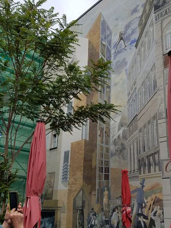 Tromp l'oeil painting of two buildings with tight rope walker between them, audience below.Art on public housing. No graffiti has appeared on this wall. It seems too fun to mess up. Richen