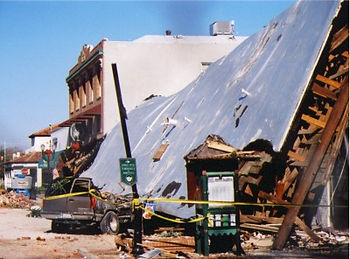Building slumped over cars after earthquake.