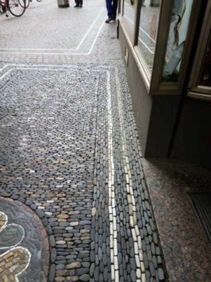 Since the street and the building fronts are sometimes curved, each design is surrounded by stripes of white rock in gray rock. The resulting rectangles are at different angles, so the pedestrians notice the change of angle as they walk along.?Richen