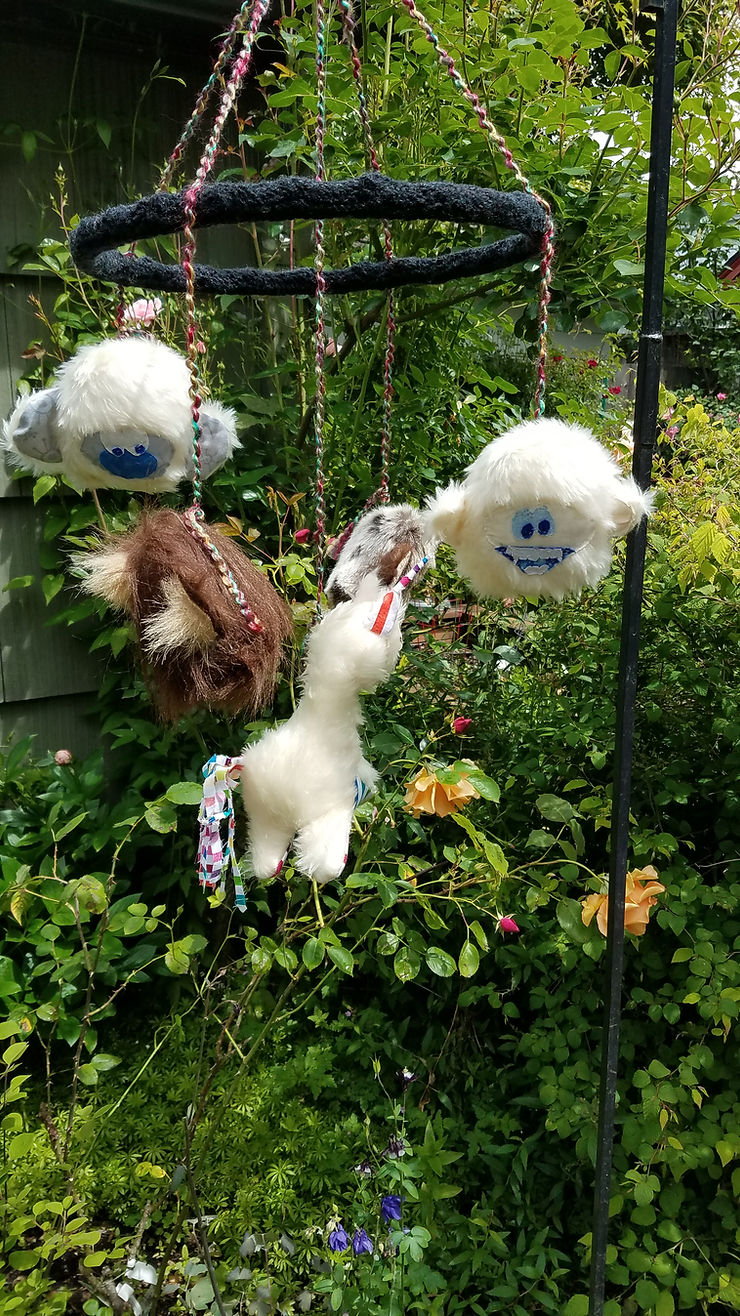 black mobile hanger, four yeti and sasquatch dolls surround the unicorn. 