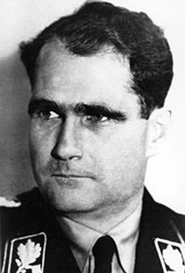 Man in Nazi uniform, dark eyebrows and wavy hair. 
