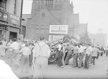 White men turning over a car. Some carrying weapons, 1940s Detroit