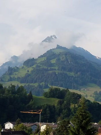 Misty mountains with hill and tower barely seen atop hill.