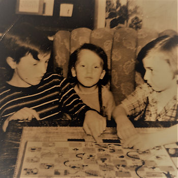 Sepia photo of Al (10 years old) teaching me (5 years) and Jim (3 years) to play Chutes and Ladders. I'm looking miffed that I can't do whatever move I just tried.es 
