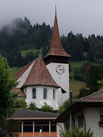 White-walled church and tower sport very steep rooves, very like the pointed hats in many medieval paintings.